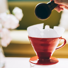 Görseli Galeri görüntüleyiciye yükleyin, Kırmızı Hario V60 02 seramik dripperın kâğıt filtresine öğütülmüş kahve eklenirken