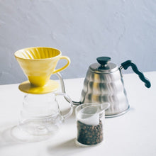 Görseli Galeri görüntüleyiciye yükleyin, Sarı Hario V60 02 seramik dripper, cam sunucu ve Buono kettle ile kahve köşesinde
